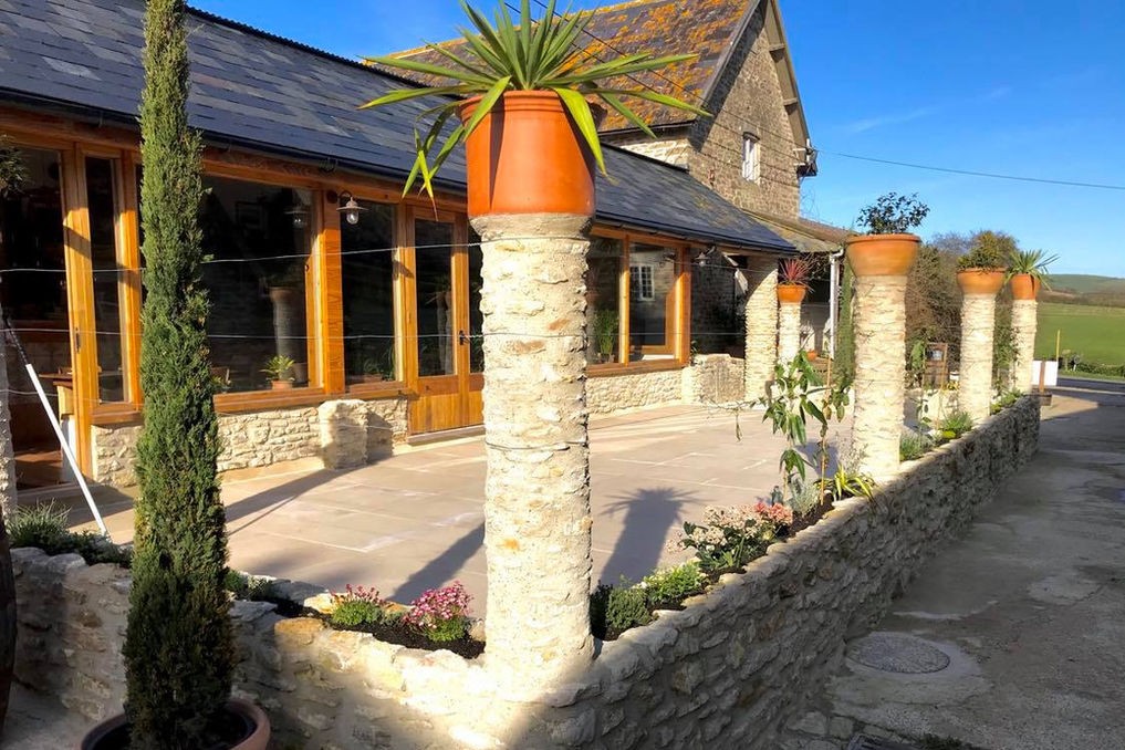 Stone pillars and potted plants outside The Parlour, Bredy Farm, Dorset